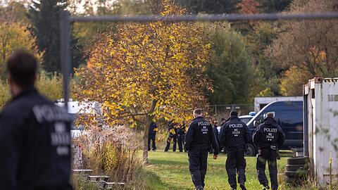 Polizisten stehen bei dem Großeinsatz auf einem Grundstück. (Archivbild)