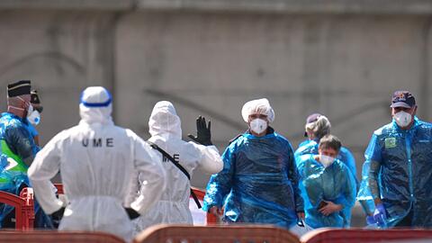Personen in Schutzbekleidung und mit Masken gehen im Hafen von Granadilla auf Teneriffa an Land.