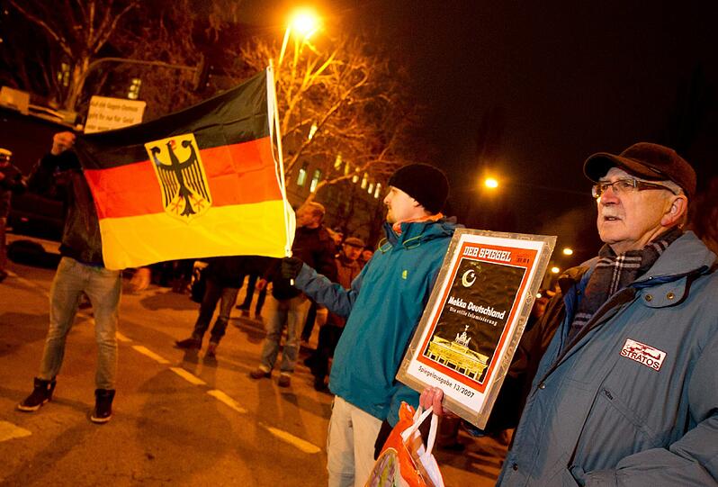 Anhänger der islamkritischen Bewegung Bagida (Bayern gegen die Islamisierung des Abendlandes) halten am 26.01.2015 eine Deutschland-Flagge und ein Titelbild des Nachrichtenmagazins "Der Spiegel".