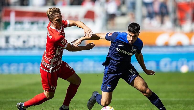 Augsburgs Robert Gumny (l) in Aktion gegen Hertha BSC Berlins Suat Serdar.