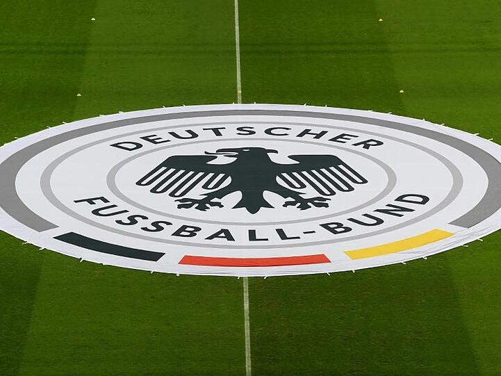 Das Logo des Deutschen Fußball-Bundes (DFB) liegt vor einem Spielbeginn auf dem Anstoßkreis. Foto: Hendrik Schmidt/Archivbild