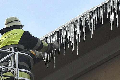 Arbeit in schwindelerregender Höhe: Ein Feuerwehrler löst die Eiszapfen von der Dachrinne.