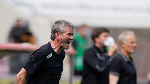 Kölns Trainer Friedhelm Funkel versucht seine Spieler auf dem Platz zu erreichen - im Hintergrund steht Freiburgs Trainer Christian Streich.