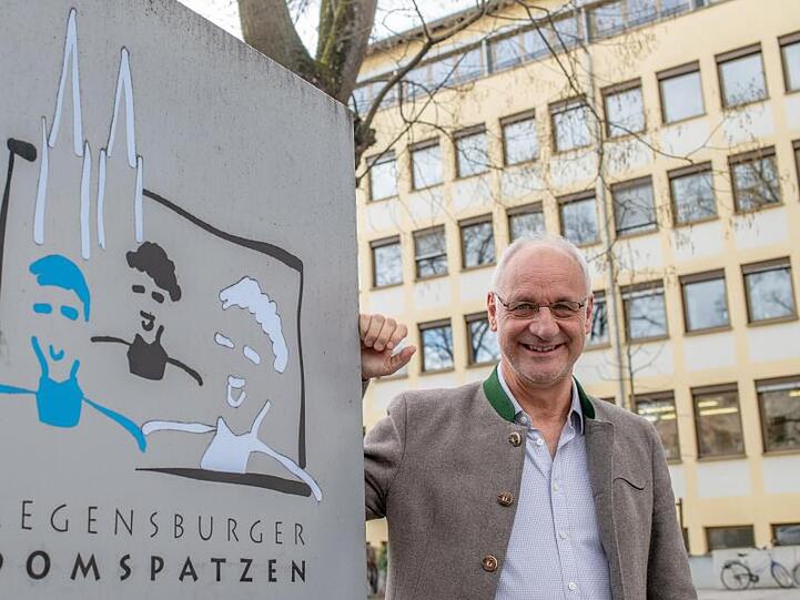Roland Büchner, Leiter der Regensburger Domspatzen steht neben einem Schild. Foto: Armin Weigel