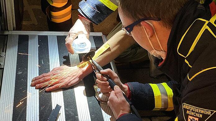 Ein Mann wird in München von der Feuerwehr und der Polizei mit einer Flex von einer Handschelle befreit.