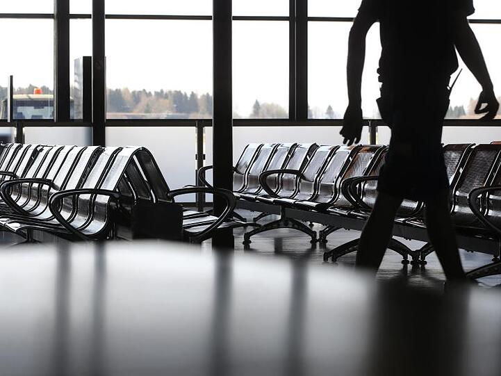 Ein Mitarbeiter läuft vor den menschenleeren Stuhlreihen im Sicherheitsbereich des geschlossenen Allgäu-Airports.