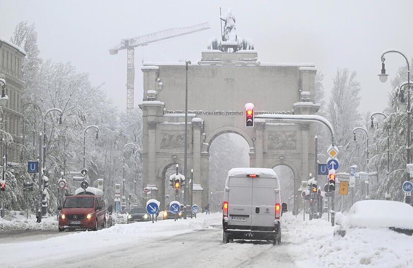 Der Verkehr rollt langsam vorbei am verschneiten Siegestor.