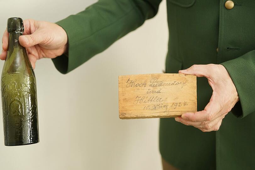 Zwei Fundstücke aus den 20er Jahren: eine leere Bierflasche eines Handwerkers und eine Holztafel, auf der sich ein Maurer verewigt hat.