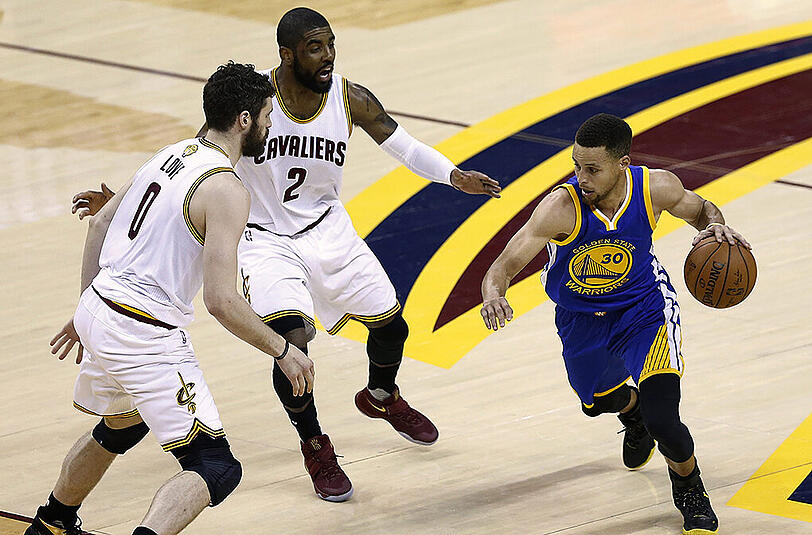 Warriors-Guard Stephen Curry (rechts) wird von den Cavaliers Kevin Love (links) und Kyrie Irving in Empfang genommen.