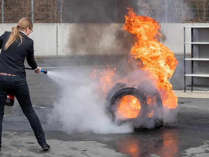 Eine Frau löscht ein Feuer mit einem Wassernebel-Feuerlöscher. Foto: Daniel Karmann