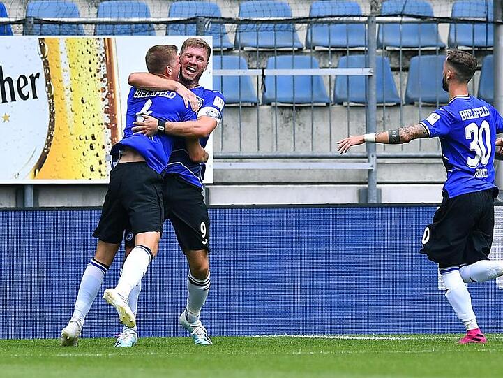 Der Bielefelder Joakim Nilsson lässt sich nach seinem Treffer von Fabian Klos und Marcel Hartel (l-r) feiern.