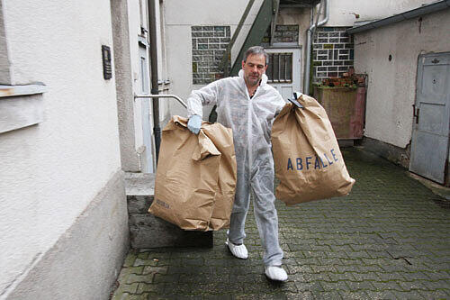 Ein Mitarbeiter der Spurensicherung transportiert in großen Müllsäcken Material vom Tatort zur Auswertung ins Labor ab.
