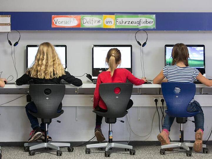 Schüler arbeiten in einem Klassenraum einer Grundschule an Computern.