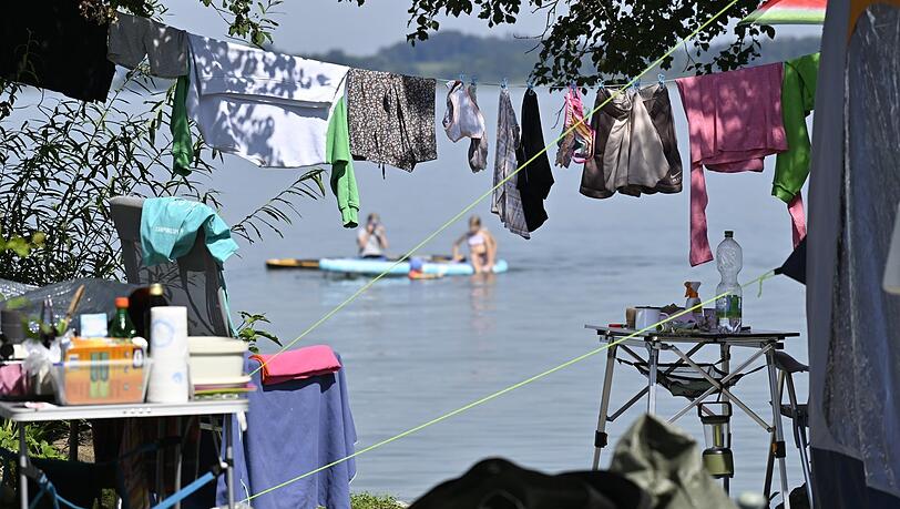 Wäsche hängt auf einem Campingplatz am Chiemsee auf der Leine vor einem Wohnmobil. Die Tourismusbranche will die Gästezahlen bayernweit besser verteilen.
