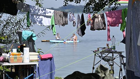 Wäsche hängt auf einem Campingplatz am Chiemsee auf der Leine vor einem Wohnmobil. Die Tourismusbranche will die Gästezahlen bayernweit besser verteilen.