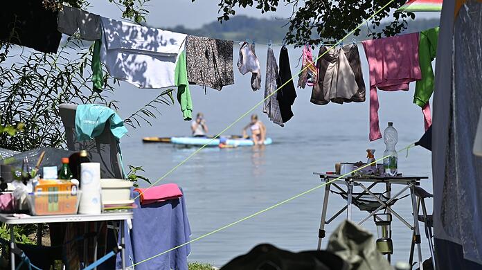 Wäsche hängt auf einem Campingplatz am Chiemsee auf der Leine vor einem Wohnmobil. Die Tourismusbranche will die Gästezahlen bayernweit besser verteilen.