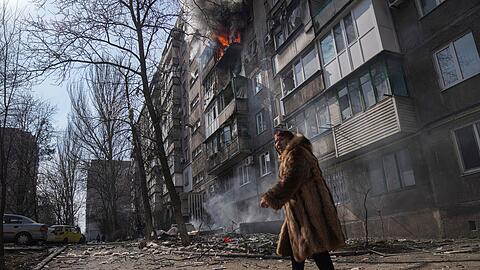 Szene aus Mariupol: Eine Frau geht an einem brennenden Wohnhaus vorbei, nachdem es beschossen wurde.