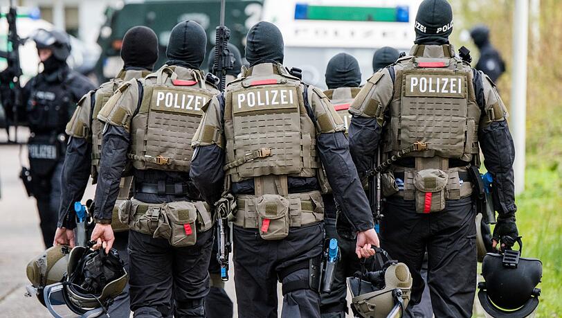 Schwer bewaffnete Polizisten gehen während einer Anti-Terror-Übung zu ihren Fahrzeugen. Schwer bewaffnete Polizisten gehen während einer Anti-Terror-Übung zu ihren Fahrzeugen.