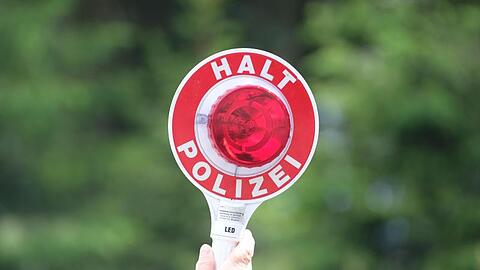 Eine Polizeikelle wird in die Höhe gehalten.