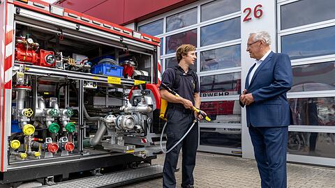 Ein Feuerwehrmann (l) präsentiert dem bayerischen Innenminister Joachim Herrmann Gerätschaften.