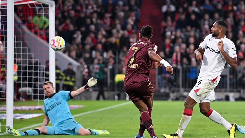 Serge Gnabry (M) von München schießt auf das Tor von Lukas Hradecky von Leverkusen.