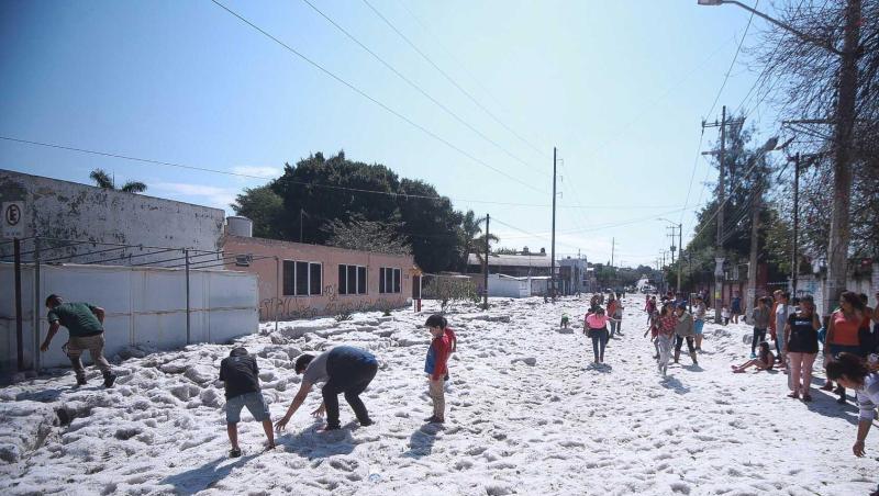 Kinder begutachten die dicke Hagelschicht auf einer Straße in der Stadt Guadalajara.