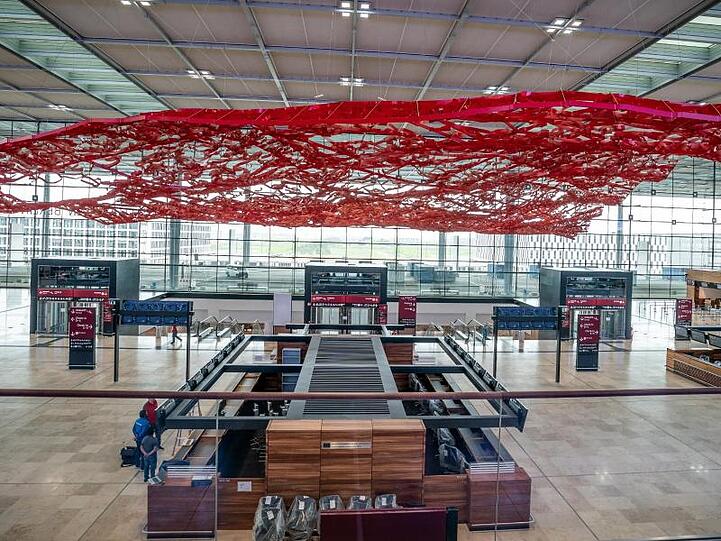Techniker und Arbeiter sind in der Abflughalle des neuen Flughafens Berlin-Brandenburg Willy-Brandt unterwegs.