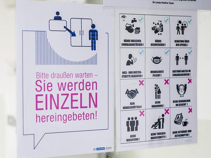 Verhaltensvorgaben weisen Kunden in einem Friseursalon über die neu geltenden Regeln im Salon hin.