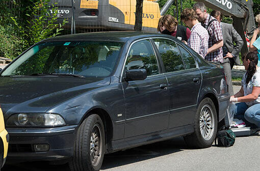 Polizisten und Spurensicherer stehen an einem Auto, hinter dem die Leiche des Schützen liegt.