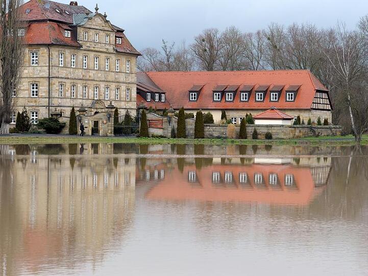 Die Seniorenresidenz Schloss Gleusdorf spiegelt sich in einer überfluteten Wiese. Foto: David-Wolfgang Ebener/Archiv