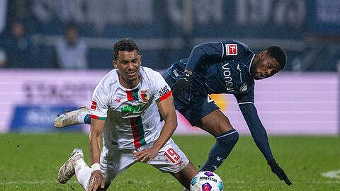 Augsburgs Felix Uduokhai (l) und Bochums Moritz Kwarteng kämpfen um den Ball.