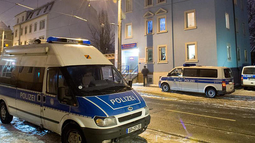 Polizeifahrzeuge stehen bei einem Großeinsatz gegen eine internationale Diebesbande vor Wohn- und Geschäftshäusern in Dresden.