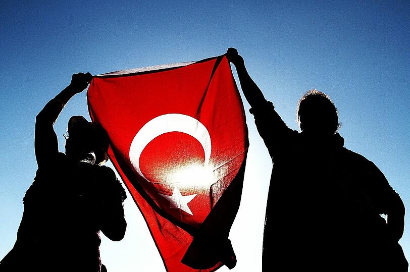 Demonstarnten halten auf dem Taksim-Platz in Istanbul eine türkische Flagge in die Luft.