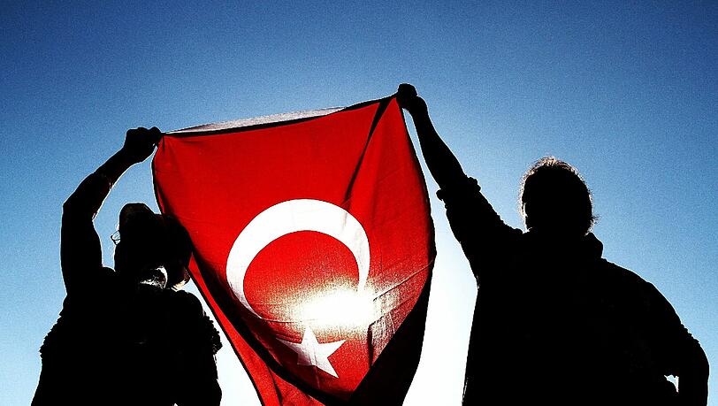 Demonstarnten halten auf dem Taksim-Platz in Istanbul eine türkische Flagge in die Luft. Demonstarnten halten auf dem Taksim-Platz in Istanbul eine türkische Flagge in die Luft.