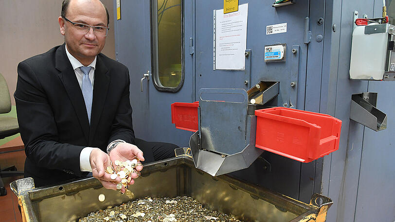 Finanzminister Albert Füracker (CSU) lässt Münzen aus einer Prägemaschine im Bayerischen Hauptmünzamt durch die Hände rieseln.