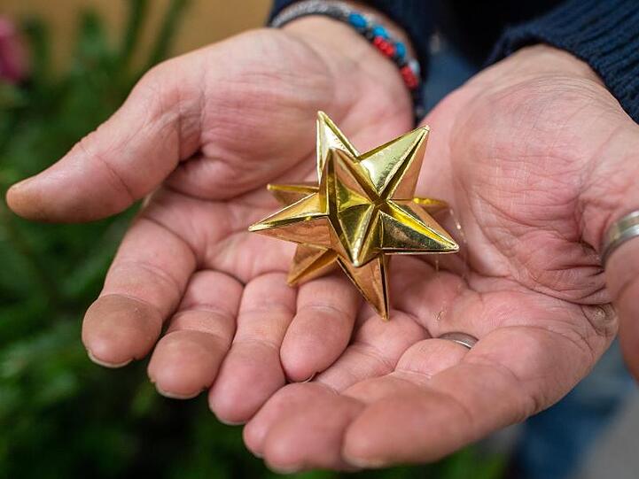 Ein Besucher einer Weihnachtsfeier für Bedürftige hält einen Stern in den Händen. Foto: Klaus-Dietmar Gabbert/zb/Archivbild