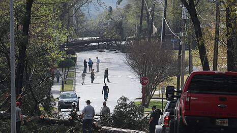 Menschen arbeiten in Cammack Village (Arkansas) daran, Bäume auf der Straße zu beseitigen, nachdem ein Tornado durch die Gegend gefegt ist.