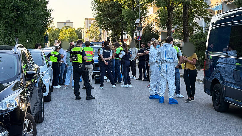 Polizisten und Beamte der Spurensicherung stehen am Tatort in Neufahrn bei Freising zusammen.