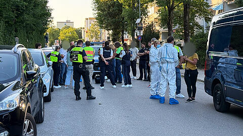 Polizisten und Beamte der Spurensicherung stehen am Tatort in Neufahrn bei Freising zusammen.