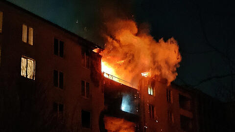 Flammen schießen aus dem Balkon und drohen auf das Dach überzugreifen.