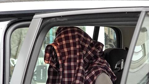 Mit Hemd über dem Kopf: Nach seiner Festnahme sitzt ein Mann in einem Auto der Einsatzkräfte.