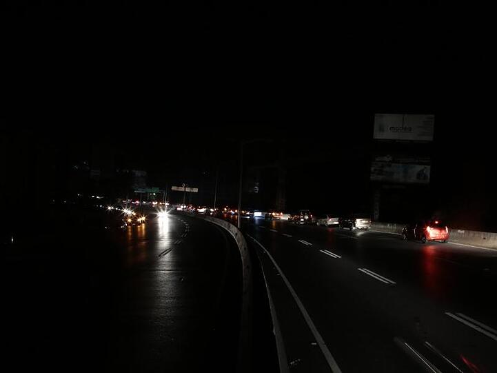 Autos fahren auf einer stockdunklen Autobahn durch die venezolanische Hauptstadt. Zwar wurden nach und nach Teile des Landes wieder an das Stromnetz angeschlossen, allerdings kommt es bei den Arbeiten ständig zu Rückschlägen.