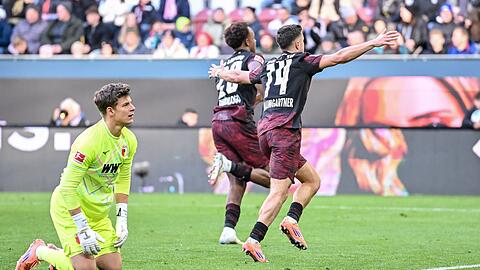 Augsburgs Torwart Finn Dahmen kauert bedröppelt am Boden, die Leipziger Assan Quedraogo (M) und Christoph Baumgartner (r) bejubeln das 0:5.