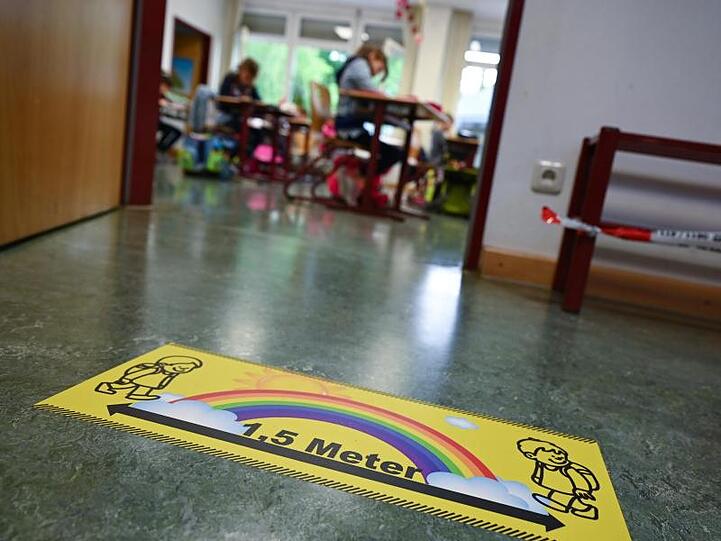 Ein Abstands-Hinweis klebt auf dem Fußboden einer Grundschule in Wiesbaden.