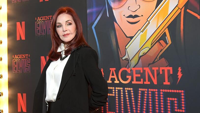 Priscilla Presley posiert vor einem Plakat der Netflix-Zeichentrickserie "Agent Elvis".