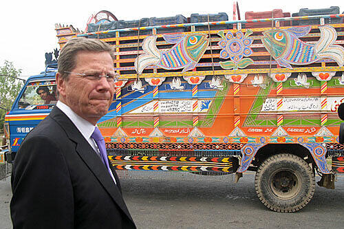 Bunte Laster in der nebligen pakistanischen Provinz, und davor ein deutscher Außenminister: Westerwelle beim Tankstopp.