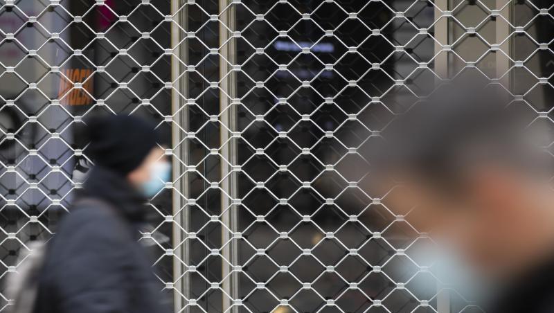 Menschen mit Mundschutz gehen an einem geschlossenen Geschäft in der Königsstraße in Stuttgart vorbei.