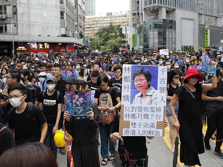 Demonstranten ziehen mit Transparenten durch das Hongkonger Viertel Mong Kok.