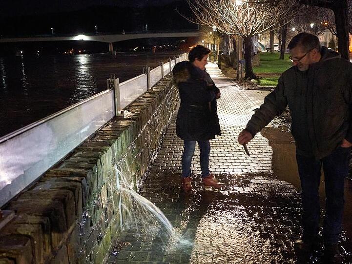 Ein Anwohner filmt mit seinem Handy in Zell eine Stelle an der Hochwasserschutzmauer, an der das Wasser der Mosel durch die Wand dringt.