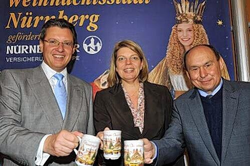 Wirtschaftsreferent Roland Fleck, Yvonne Coulin, Geschäftsführerin der Tourismuszentrale und Schausteller-Boss Lorenz Kalb (von li.) stellen die offizielle Glühweintasse 2010 vor. Passend zum Bahn-Jubiläum ist darauf heuer der &bdquo;Adler&ldquo; abgebildet.